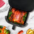 Detaillierter Einblick in TESLA AirCook Q60 XXL Pro Fritteuse beim Braten eines ganzen Hähnchens mit Gemüse, in der durchsichtigen Schublade des Geräts.